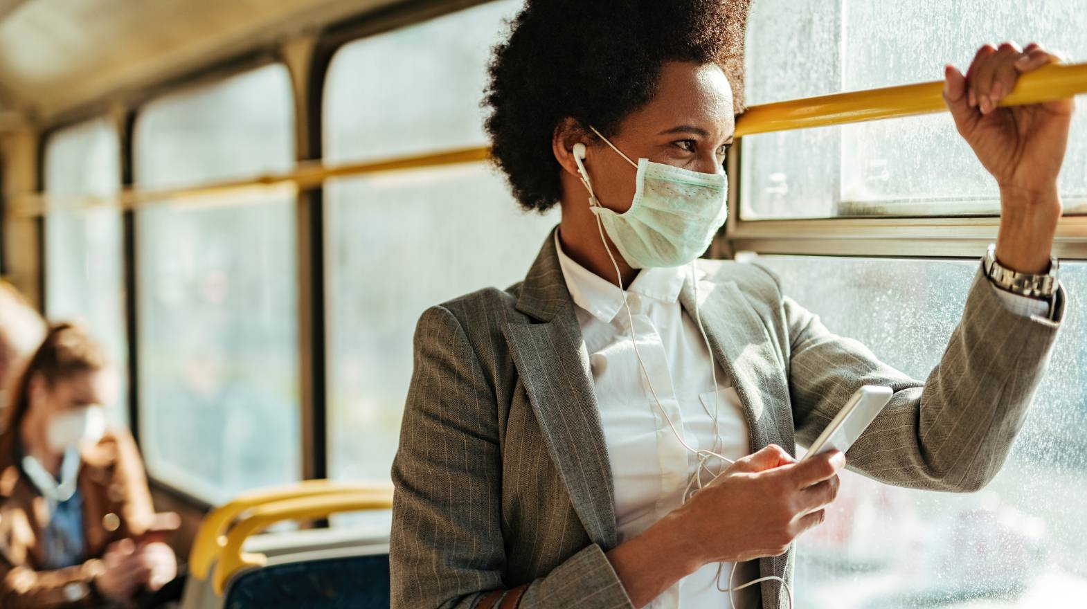 Woman with medical mask looking outside of public transportation window