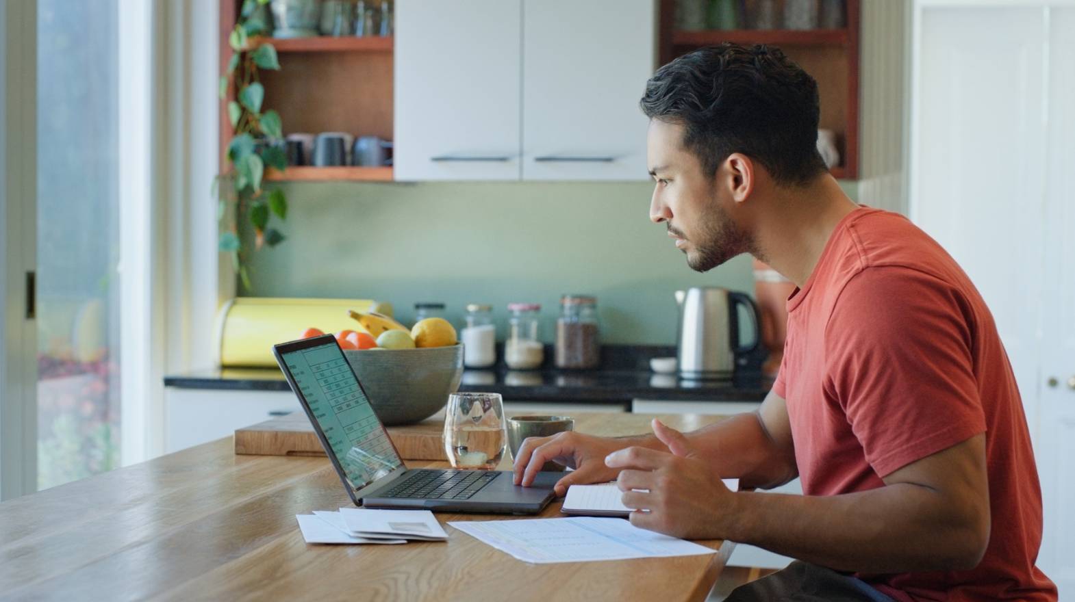 Serious man working from laptop in home kitchen