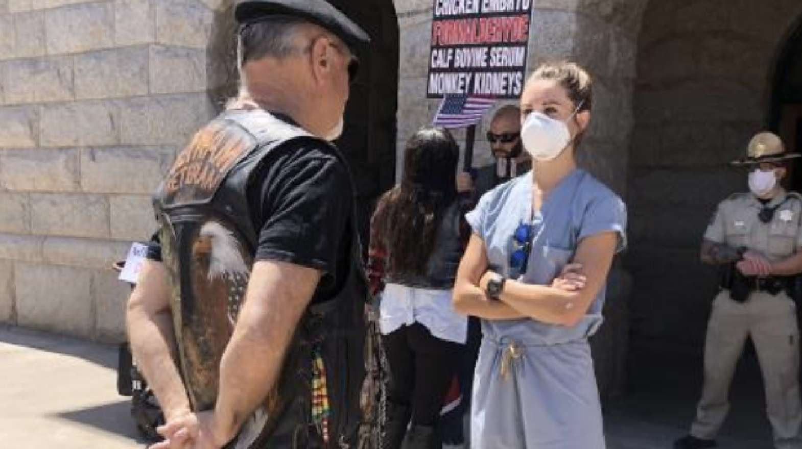 Older rugged gentleman standing in front of determined nurse holding her arms crossed