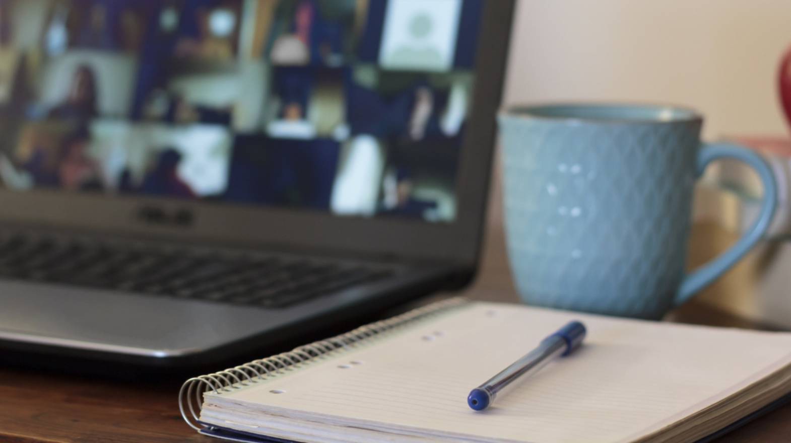 Empty notebook and pen on desktop next to laptop